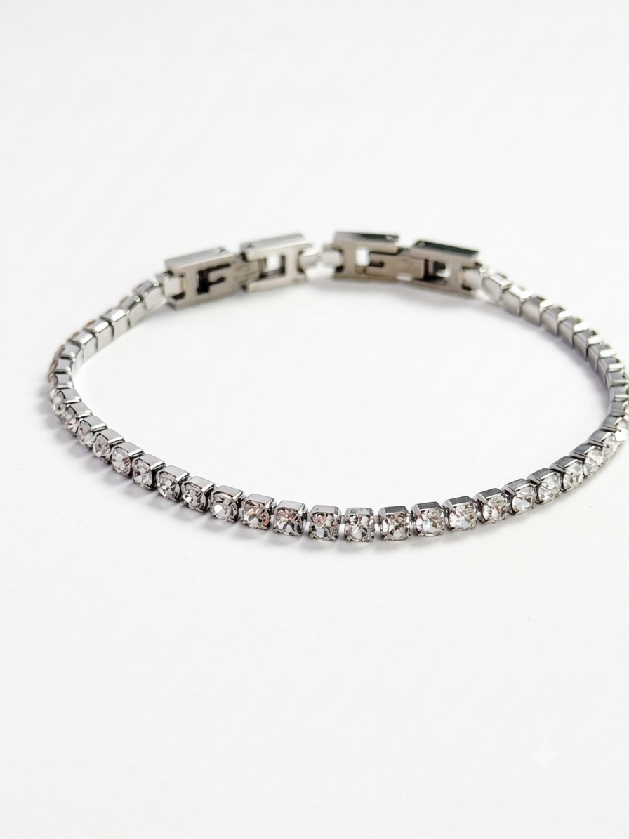 A silver-toned tennis bracelet with a row of clear stones and a clasp, displayed on a clean white background.