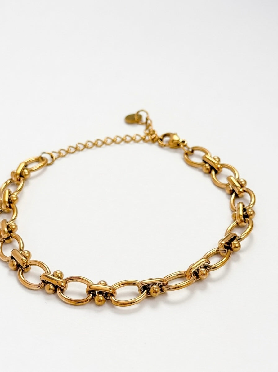 A gold-toned chunky chain link bracelet with a delicate extender chain and clasp, displayed on a clean white background.