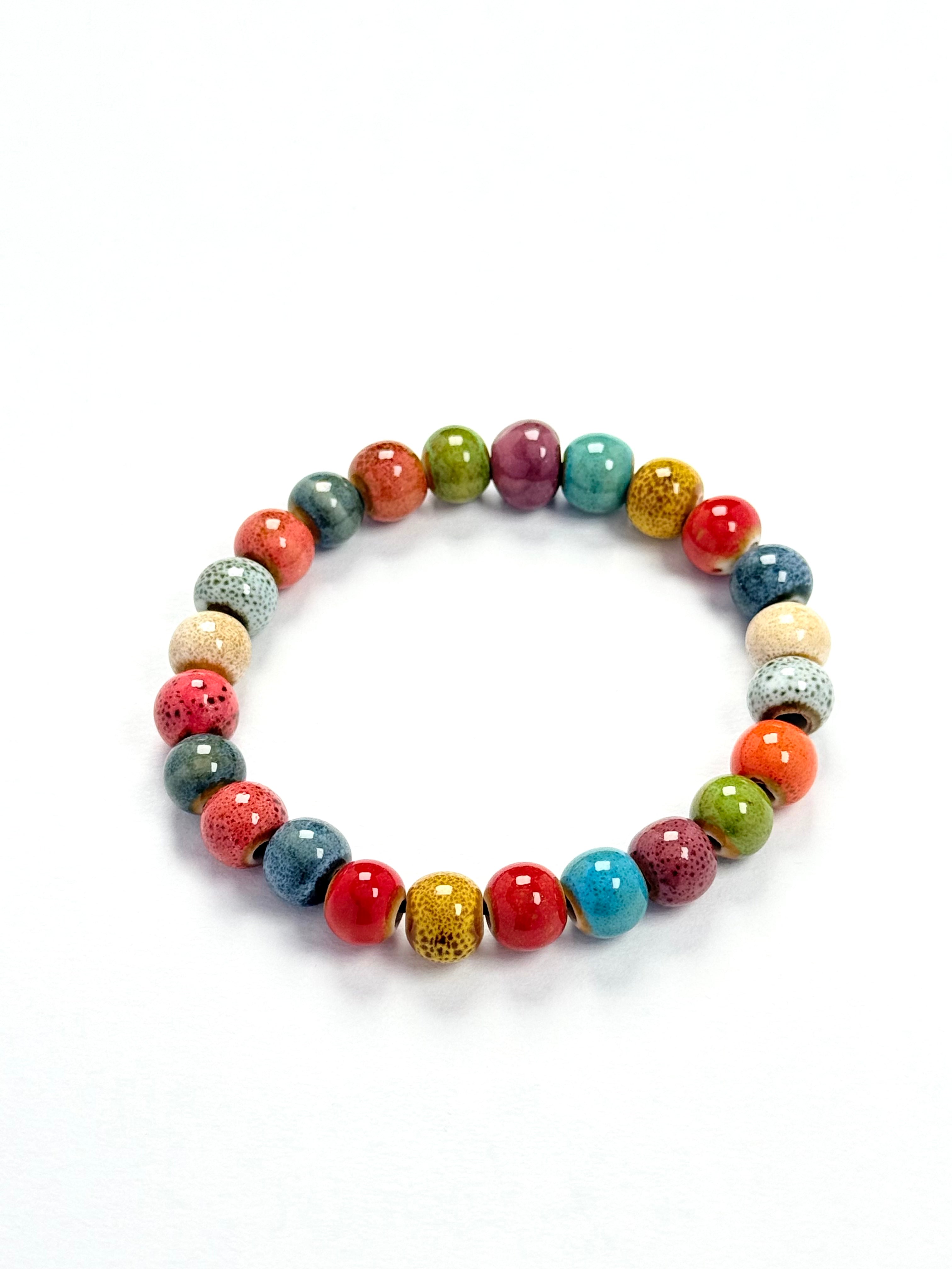 A beaded stretch bracelet made of glossy, round ceramic-like beads in multiple vibrant colors including red, blue, green, orange, yellow, purple, and speckled gray, arranged in a circle on a white background.