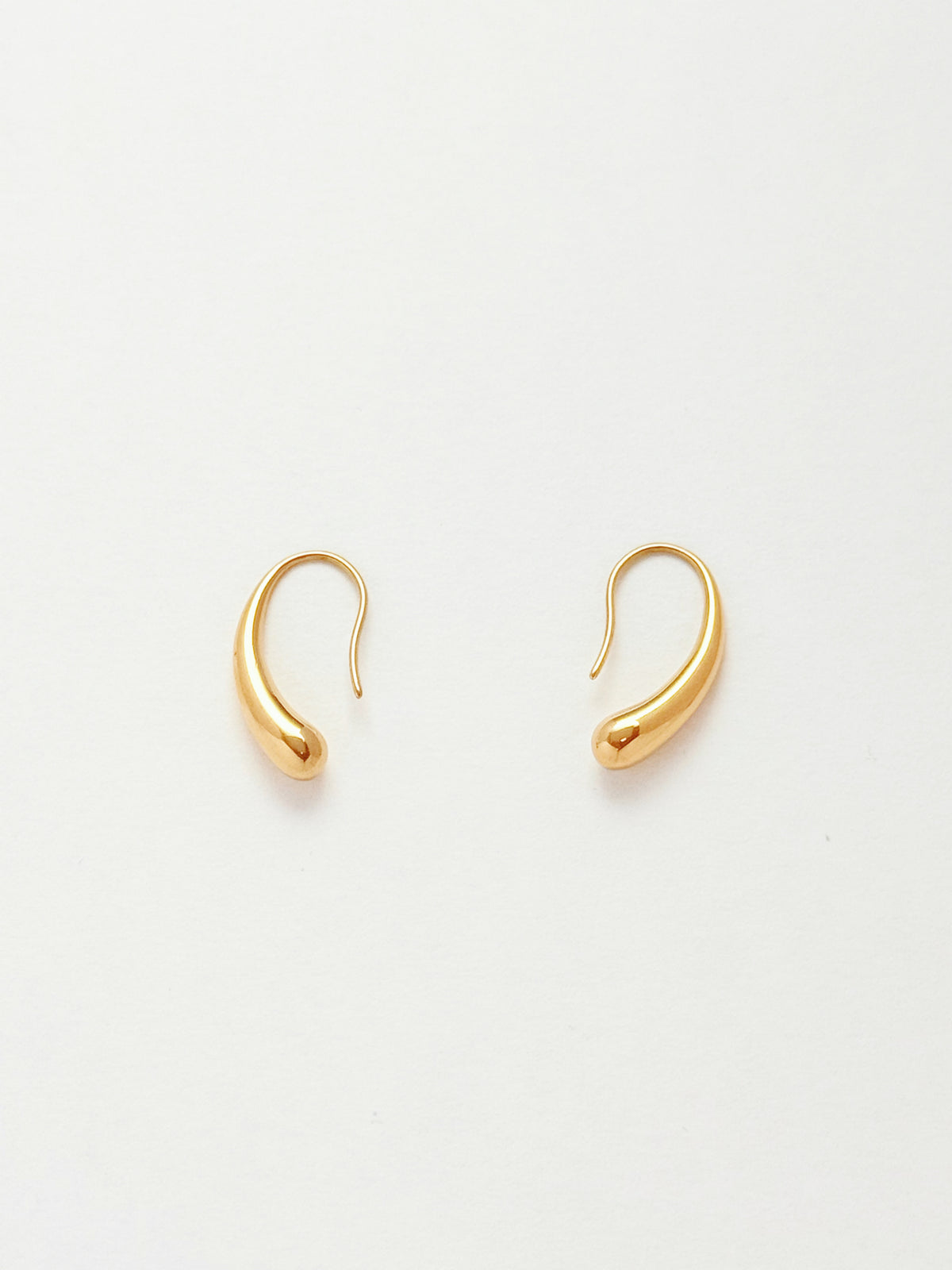 A pair of gold-colored, curved teardrop-shaped dangle earrings on a clean white background.