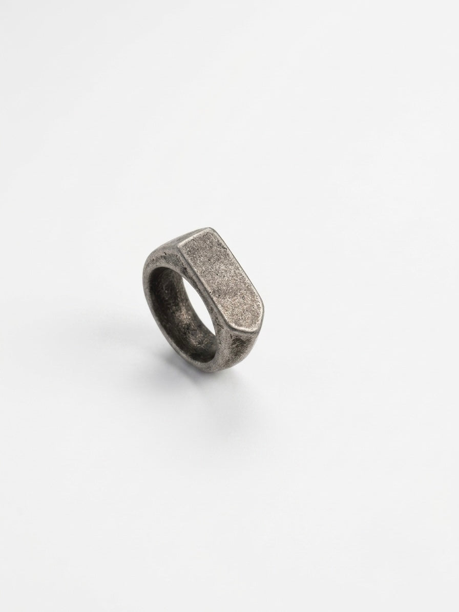 A textured silver signet-style ring with a rectangular face, photographed on a clean white background.