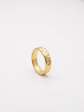 A textured yellow gold band ring with a small starburst detail and a tiny clear gemstone.